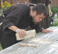Brother Joshua van Cleef, O.F.M. sands a picnic table for Our Lady Queen of Peace Parish in Arlington, Virginia.